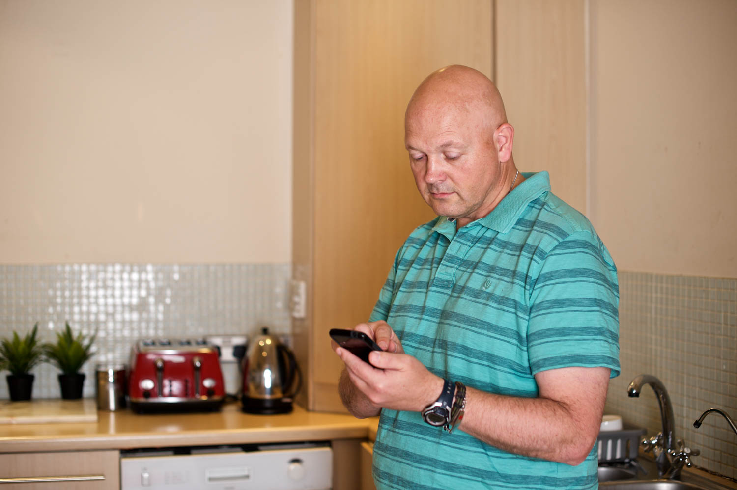 A man looking at his phone in the kitchen
